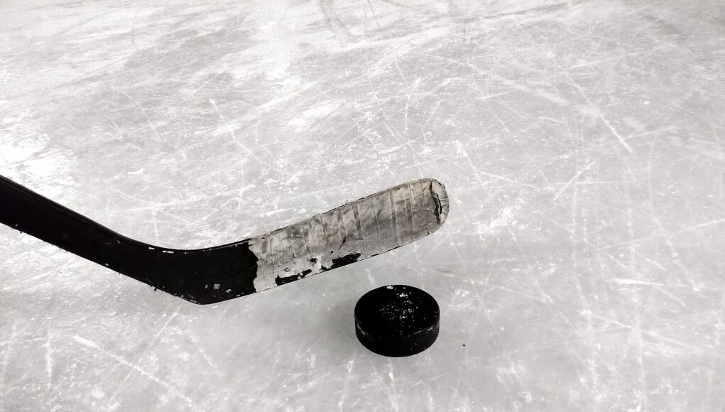 An ice hockey stick and puck resting on rink ice